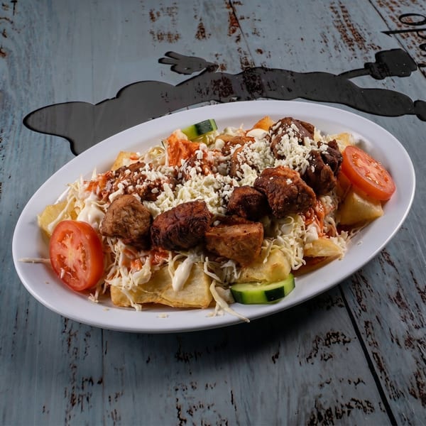 A white oval plate filled with fried pork chunks, shredded cabbage, tomatoes, and cheese.